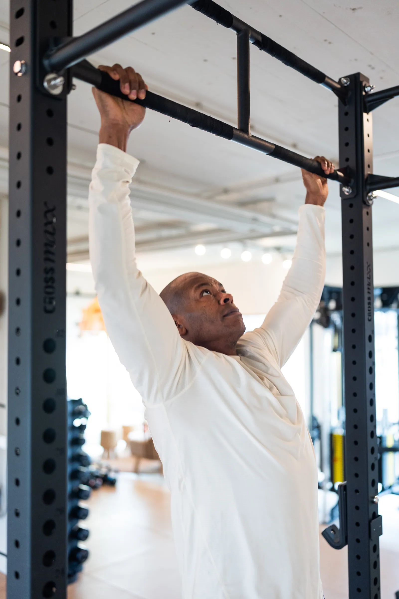 Man hangt aan pull-upstang in power rack met geconcentreerde blik.