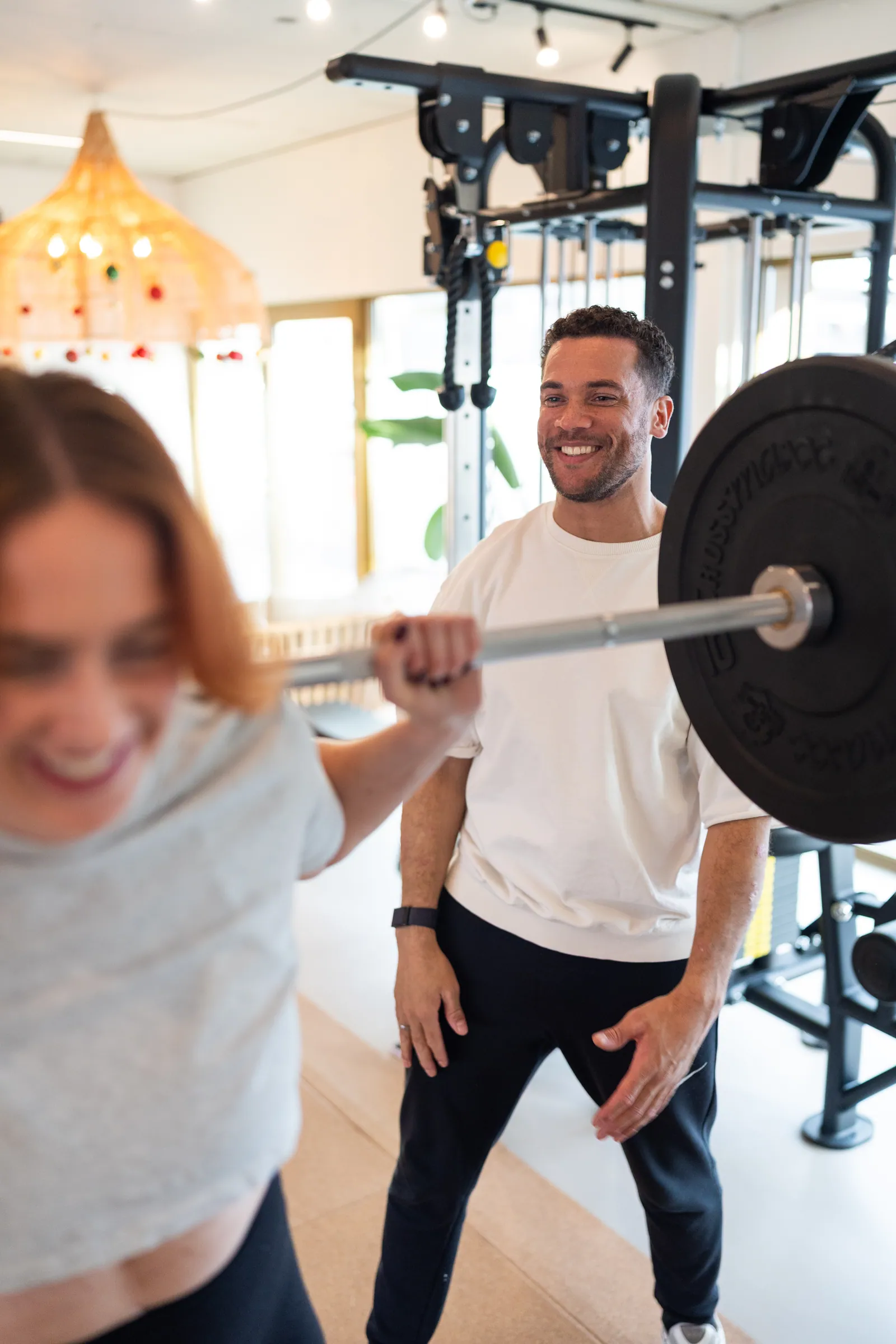 Coach naast atlete tijdens back squat met barbell